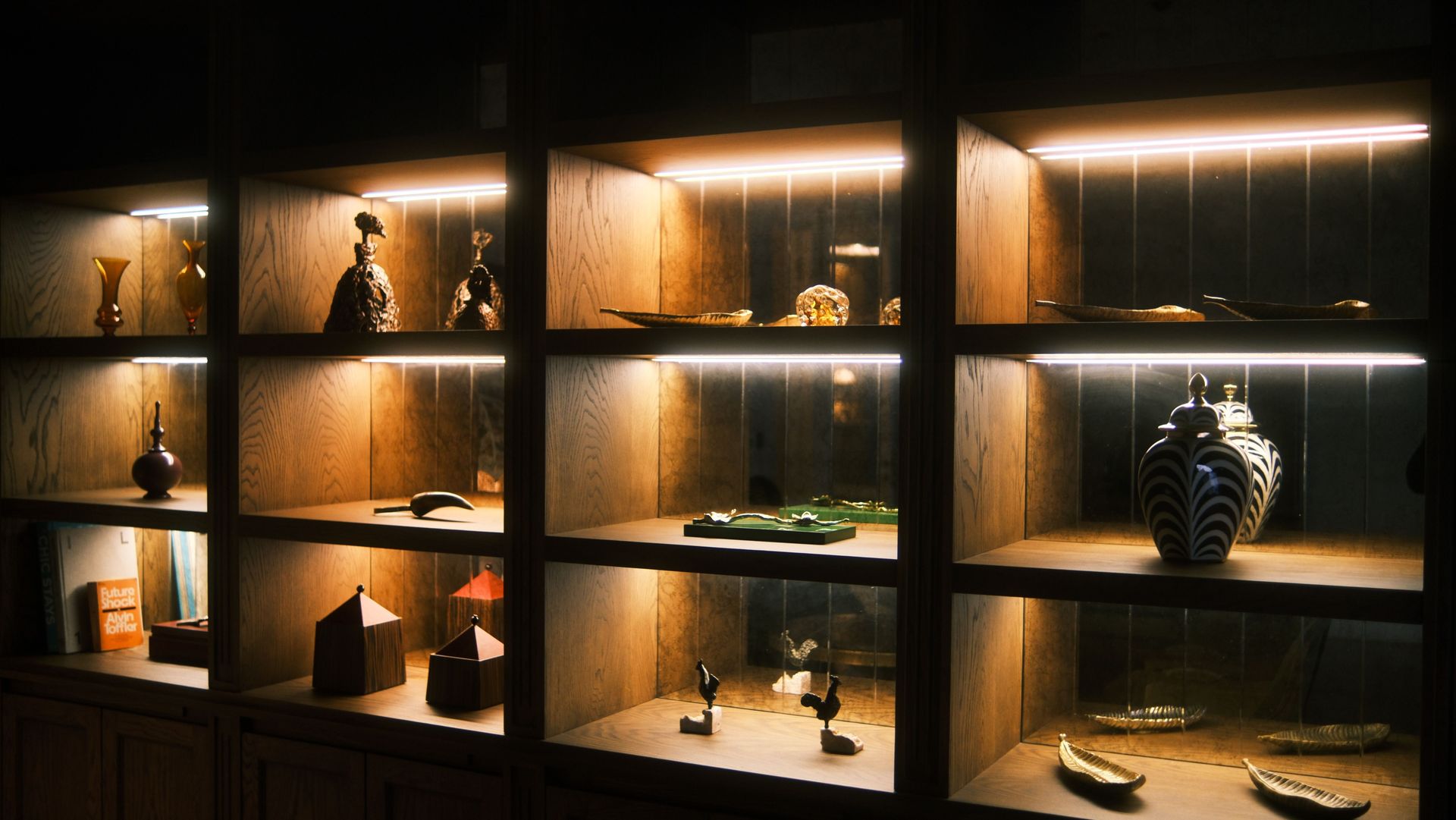 Wooden display shelves with artistic ceramics and sculptures elegantly lit for a warm ambiance.
