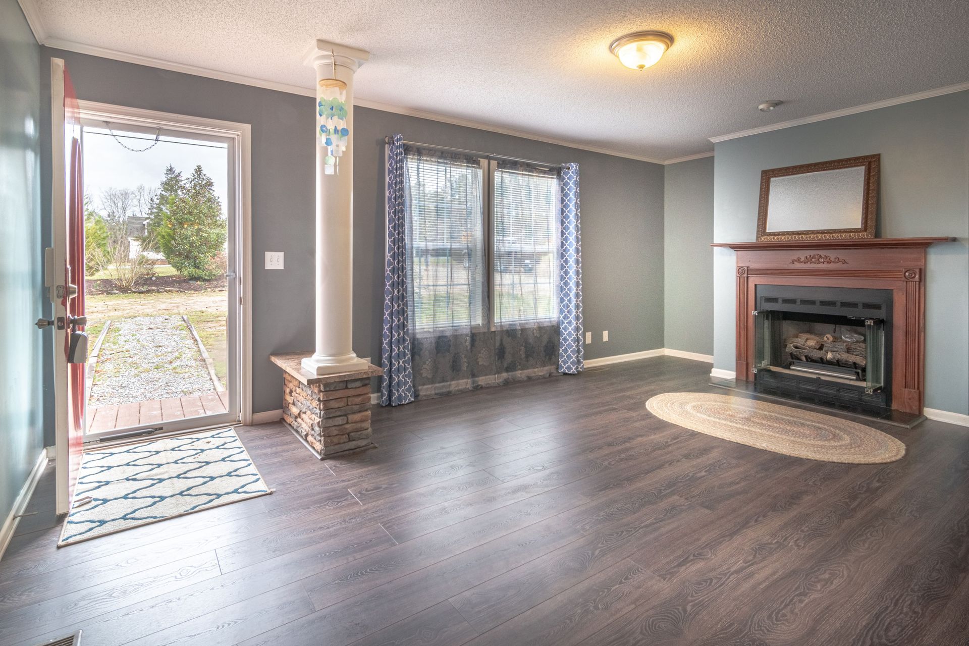 Inviting living room with fireplace, large windows, and open door leading outside.